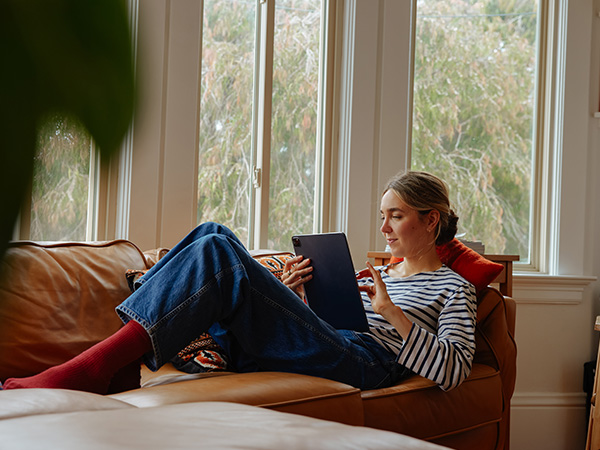 Kvinna sitter i en soffa och läser.