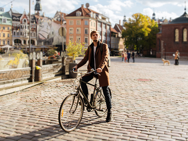 Cyklist som väntar på ett torg.